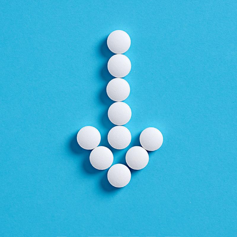 White circular pills arranged into the shape of a downward-pointing arrow