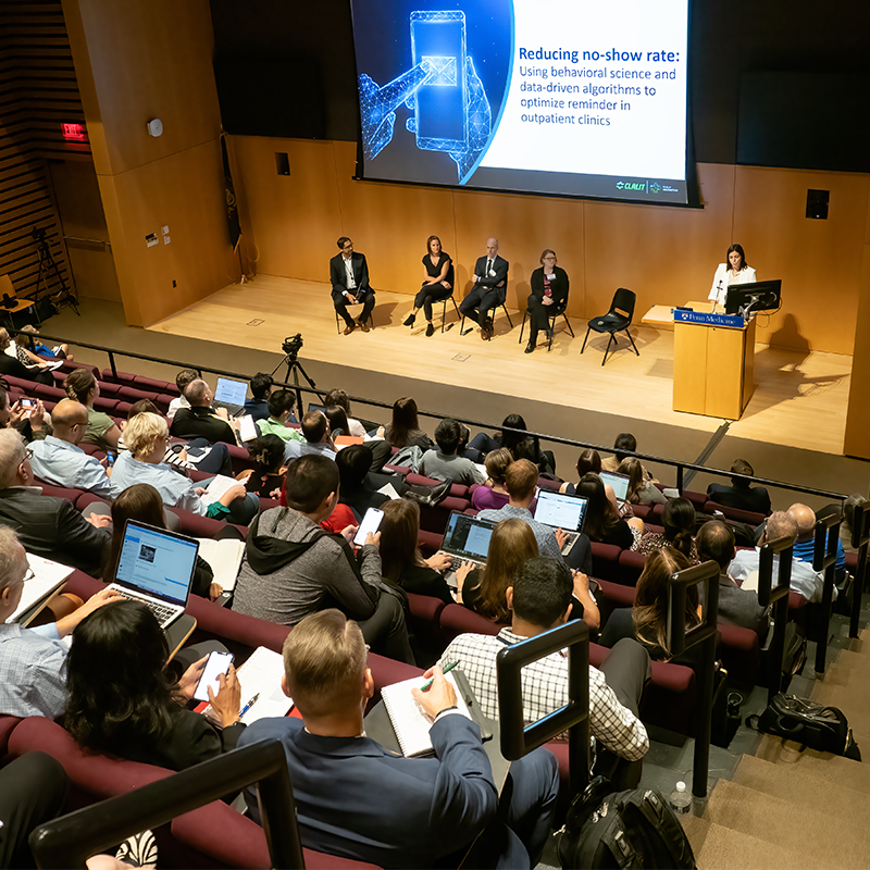Auditorium with panelists on stage during the Nudge symposium