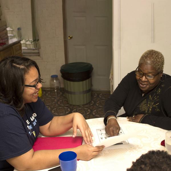Community health worker and an older woman at a table pointing at a piece of paper